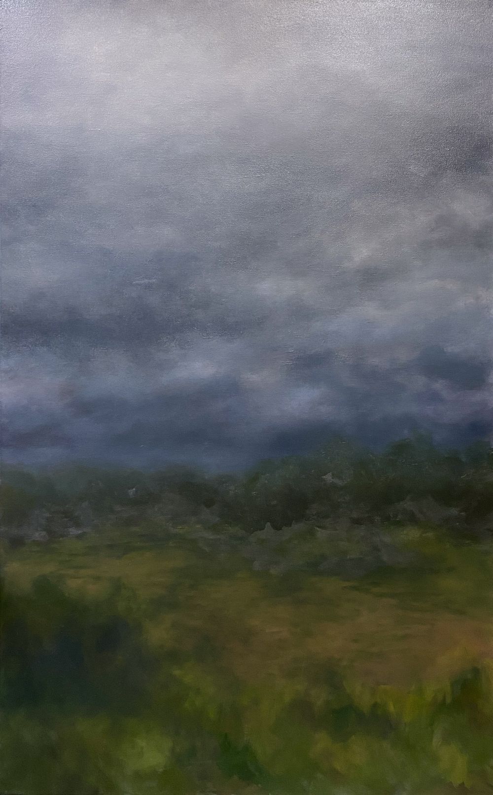 Moody landscape with dark storm clouds looming over green rolling hills.