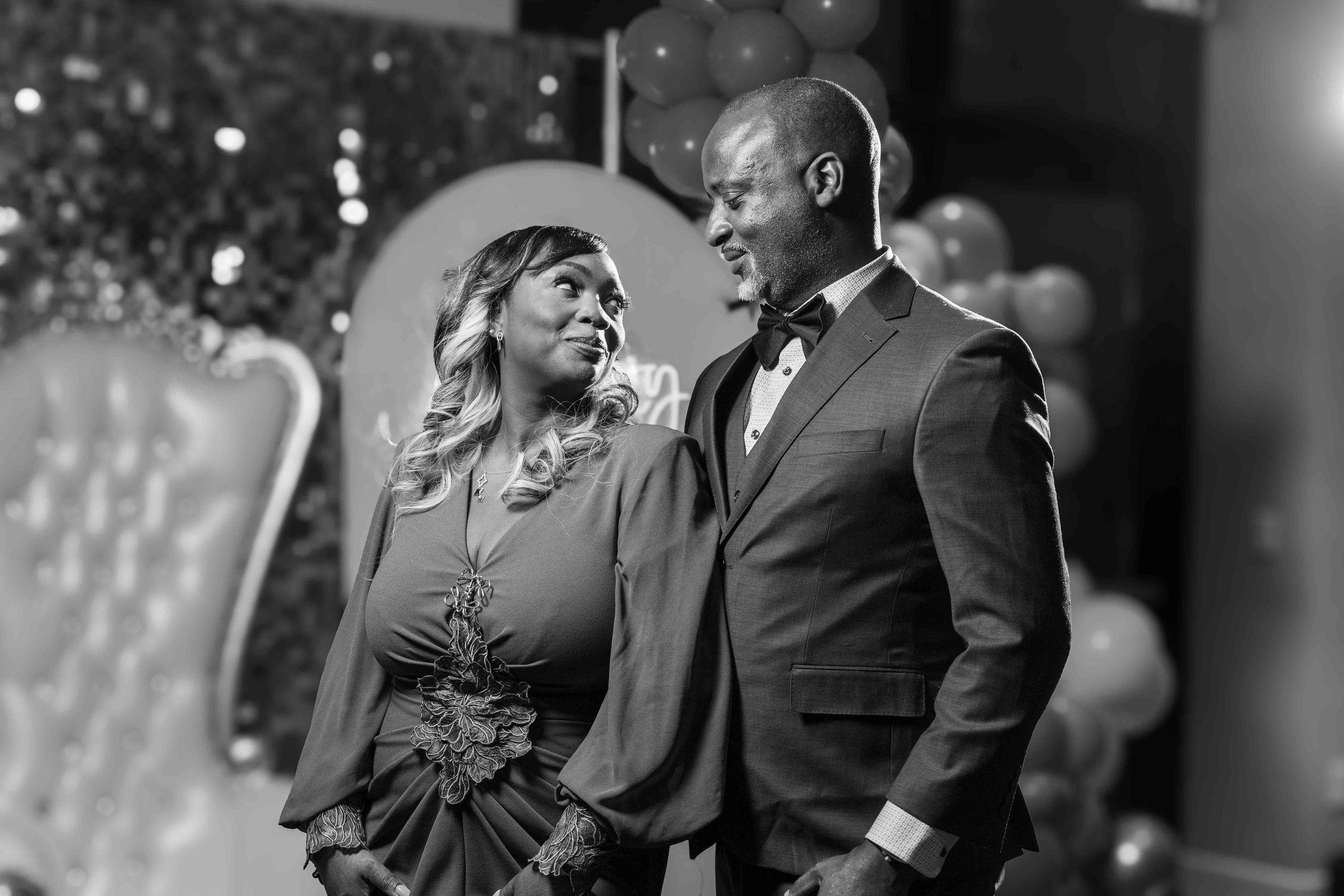 A candid black and white photo of two people sharing a joyful moment at a formal event.