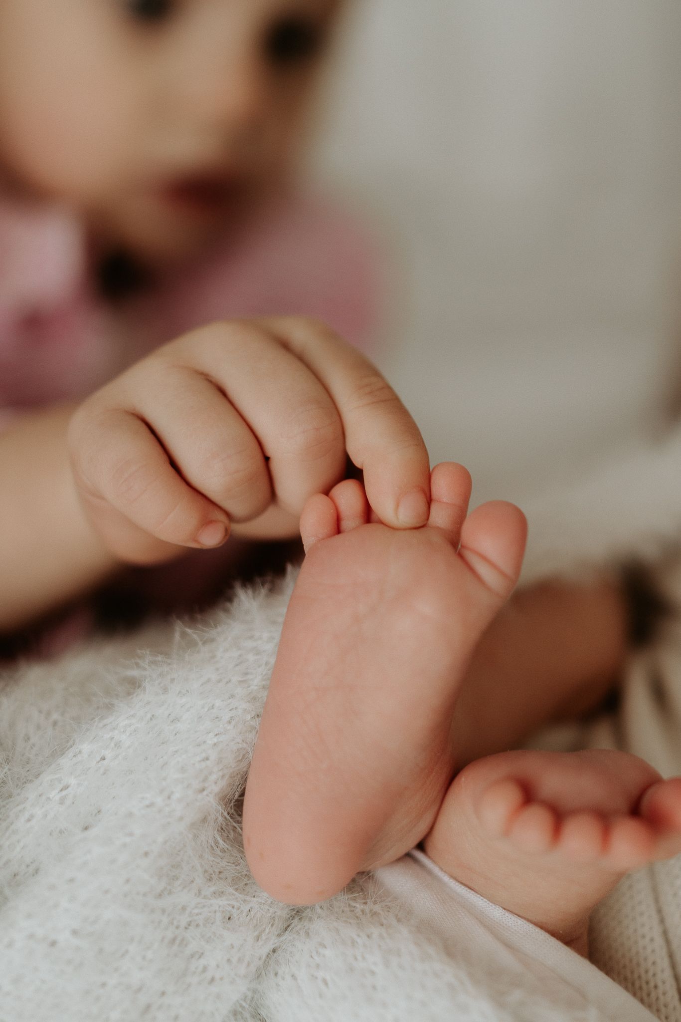 Children in white shirts sitting together with baby sibling in blue romper.