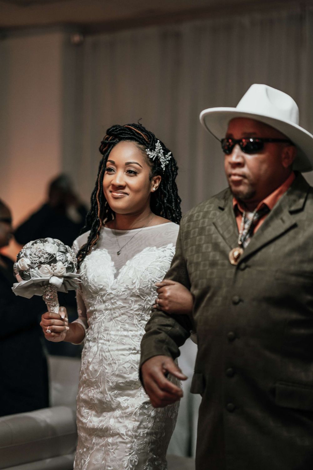 A wedding celebration moment captured indoors with the bride holding a bouquet.