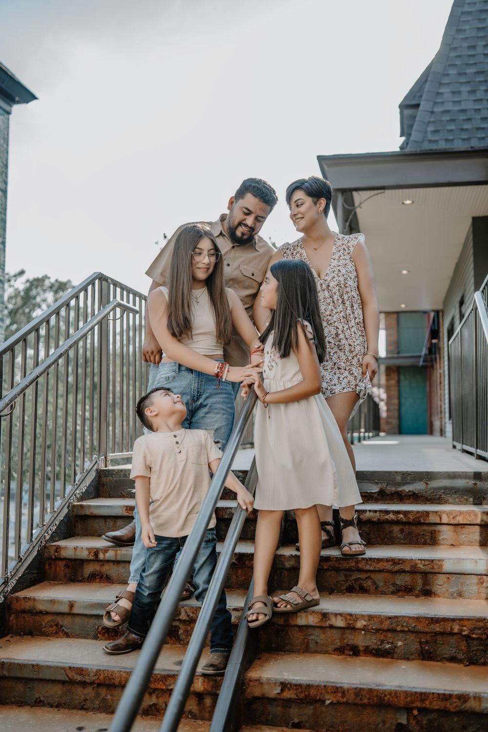 A family gathered together on outdoor stairs of a building on a sunny day.