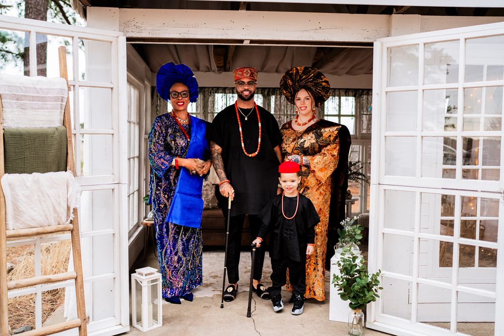 A group of people stand in front of white French doors during what appears to be a social gathering.