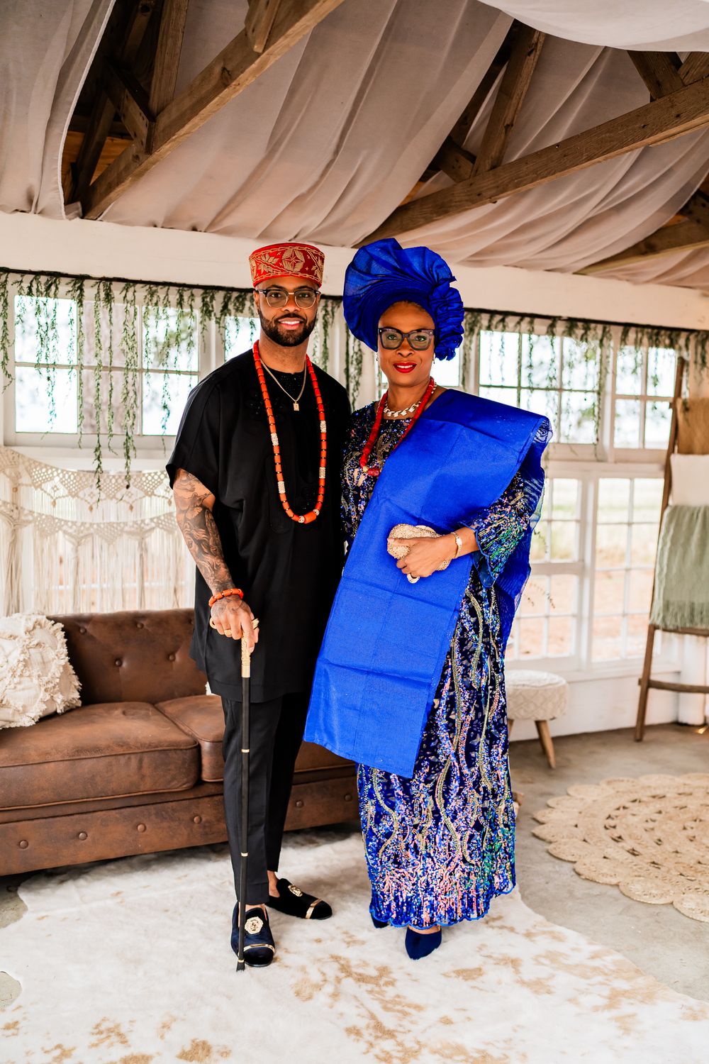 Traditional Nigerian couple in coordinated blue and black attire pose together in a draped wedding venue setting.