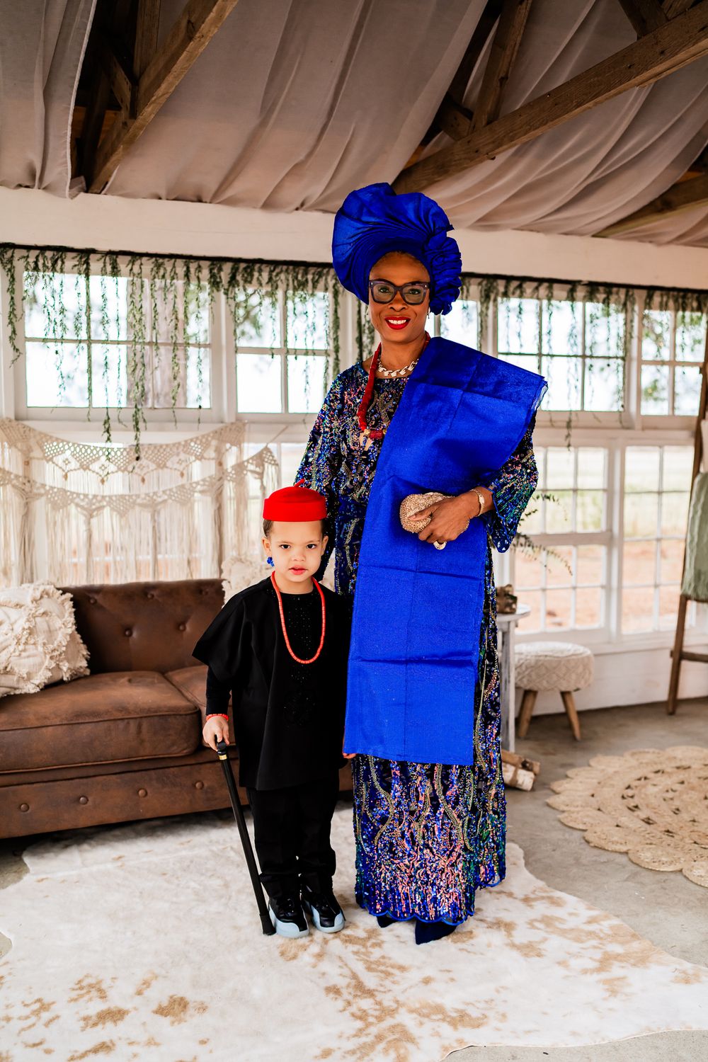 Traditional African attire featuring vibrant royal blue headwrap and dress with colorful patterns in an elegant indoor setting.