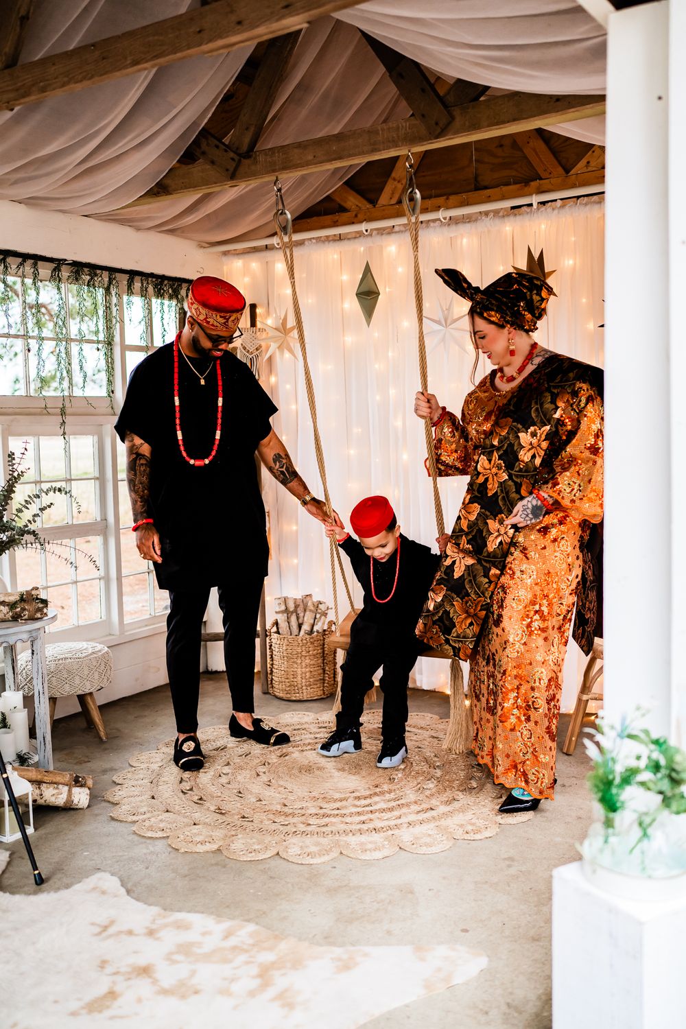 Two people in red berets and casual attire dance playfully in a white tent-like space with draped fabric decor.