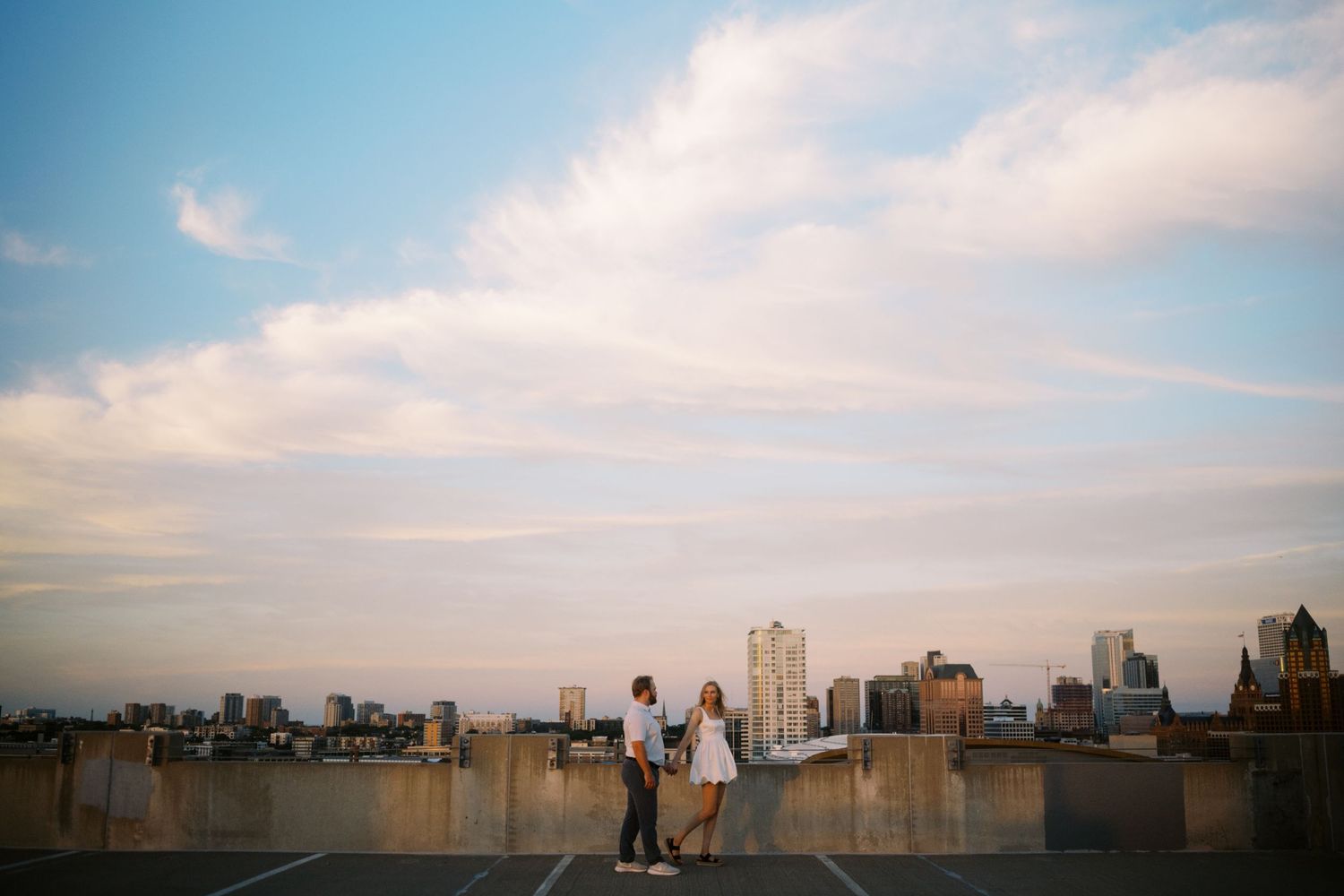 People enjoying sunset views of an urban skyline from a city rooftop on a hazy summer evening.