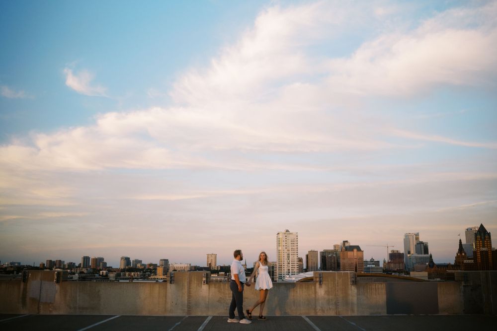 People enjoying sunset views of an urban skyline from a city rooftop on a hazy summer evening.