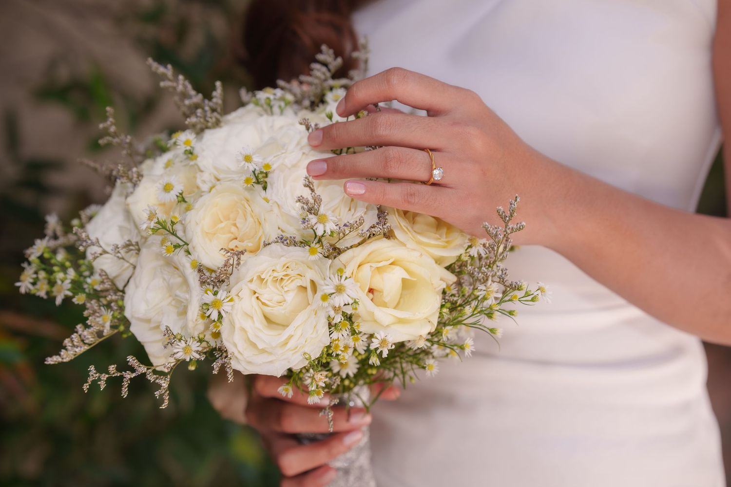 Close up of delicate white rose and baby's breath wedding bouquet with pearl accents.