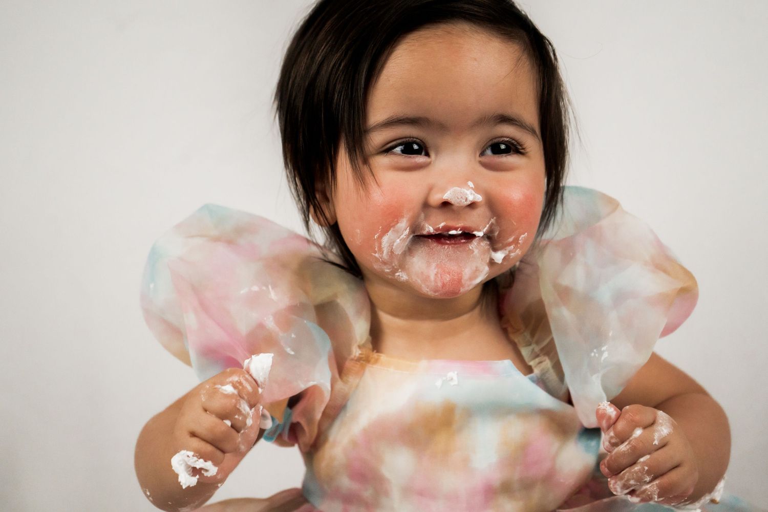Joyful child wearing pink dress playing and getting messy.