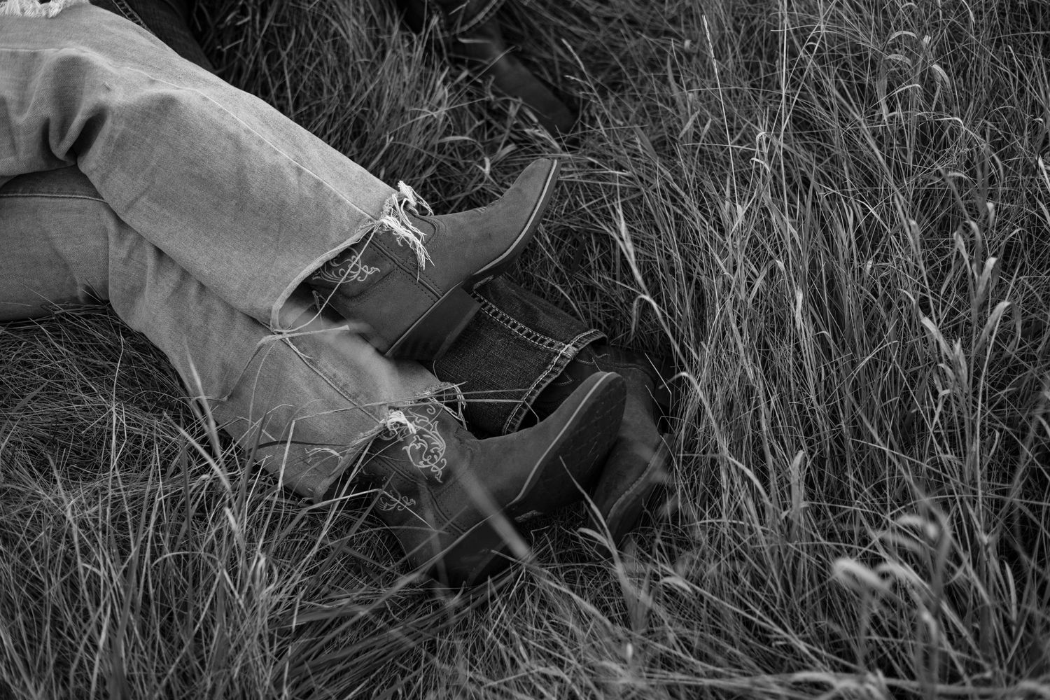 Black and white image of boots and legs lying in tall grass. West Michigan.
