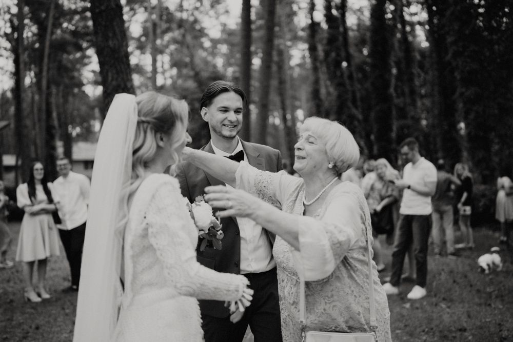 Guests enjoying a casual outdoor wedding celebration in the woods.