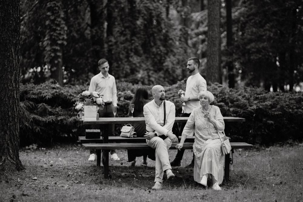 People relaxing on benches at an outdoor wedding reception.