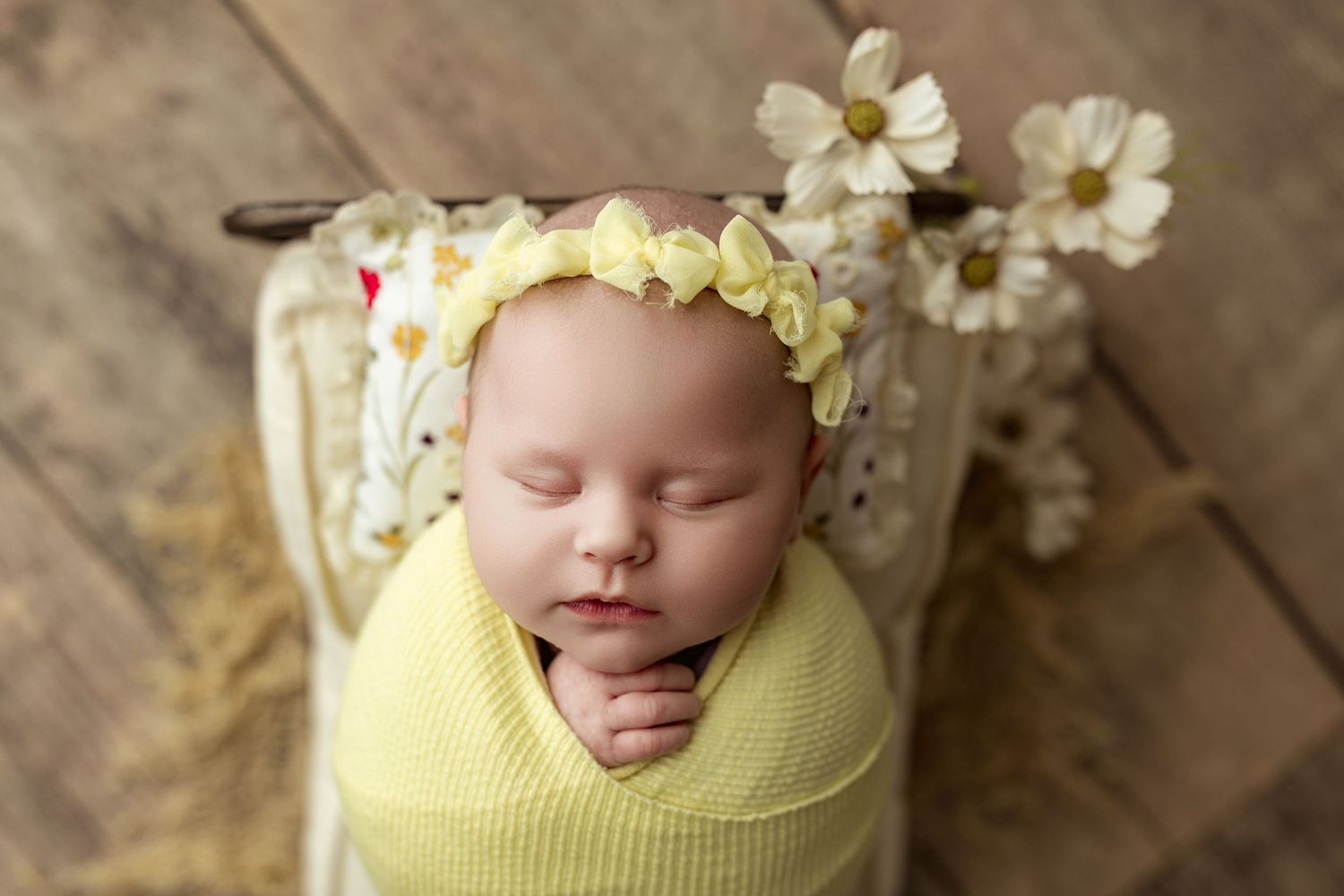 Sleeping newborn baby wearing gold floral crown headpiece rests peacefully on brown backdrop during professional photoshoot in Dayton Ohio