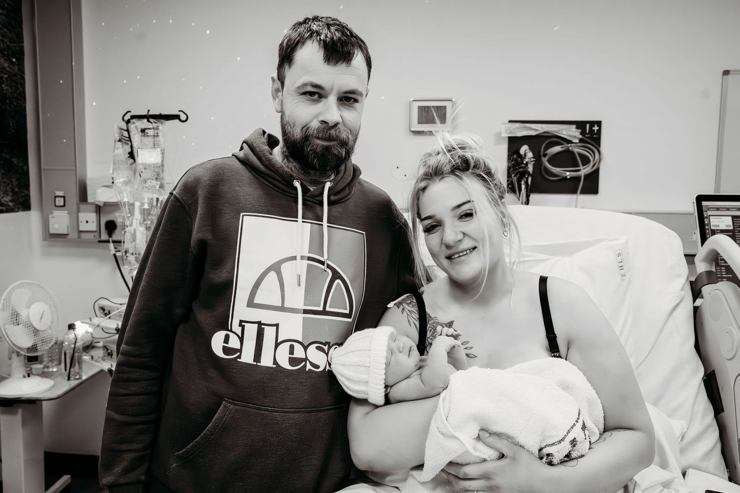 New parents in hospital room with newborn baby share happy moment together.