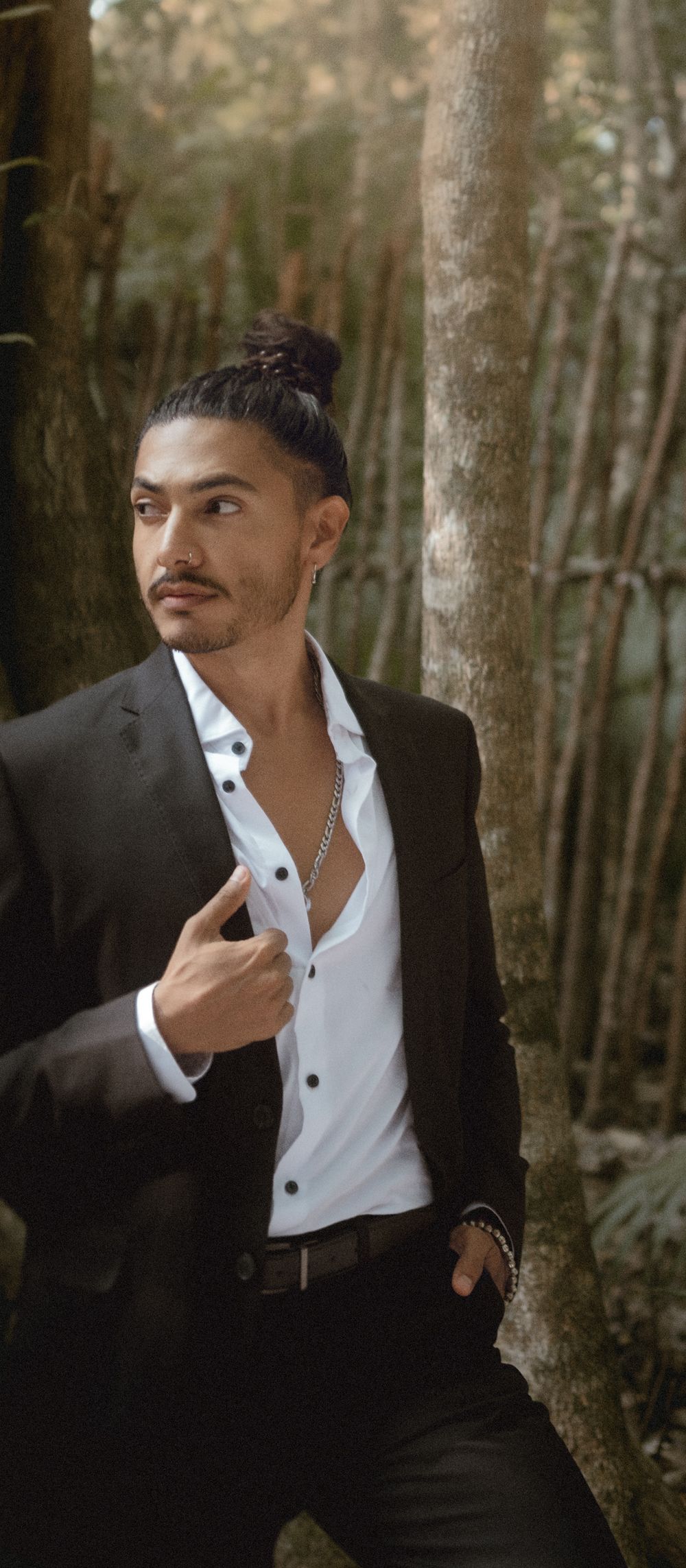 Stylish fashion portrait against bamboo forest backdrop showing dark suit and white shirt combination.