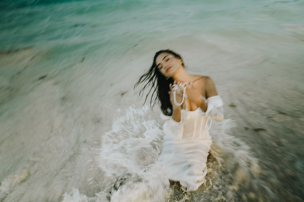 Ethereal underwater fashion photo with flowing white dress and splashing waves.