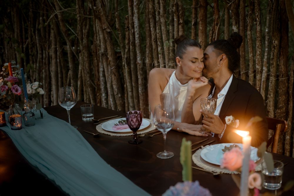 Romantic candlelit dinner scene with couple at rustic wooden table.