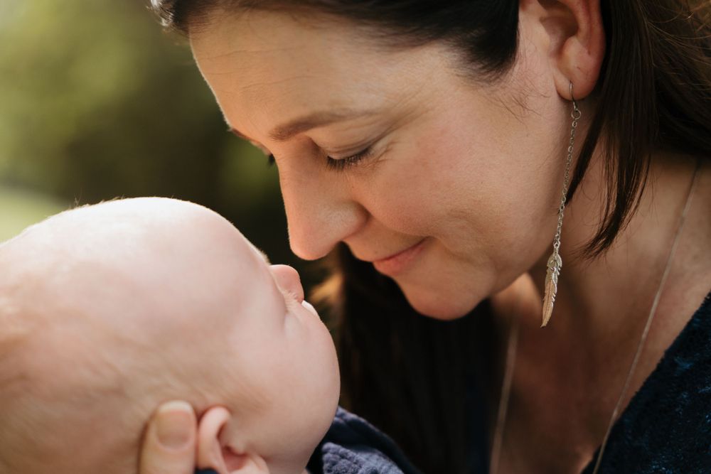 A tender moment between parent and baby as they share a close embrace outdoors.