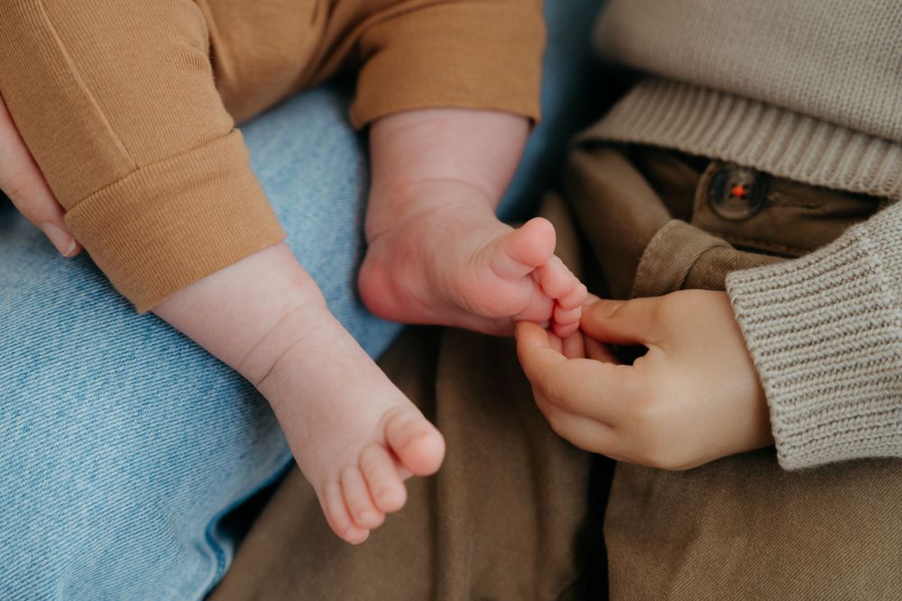 Small baby feet and hands touch gently in an intimate family moment.