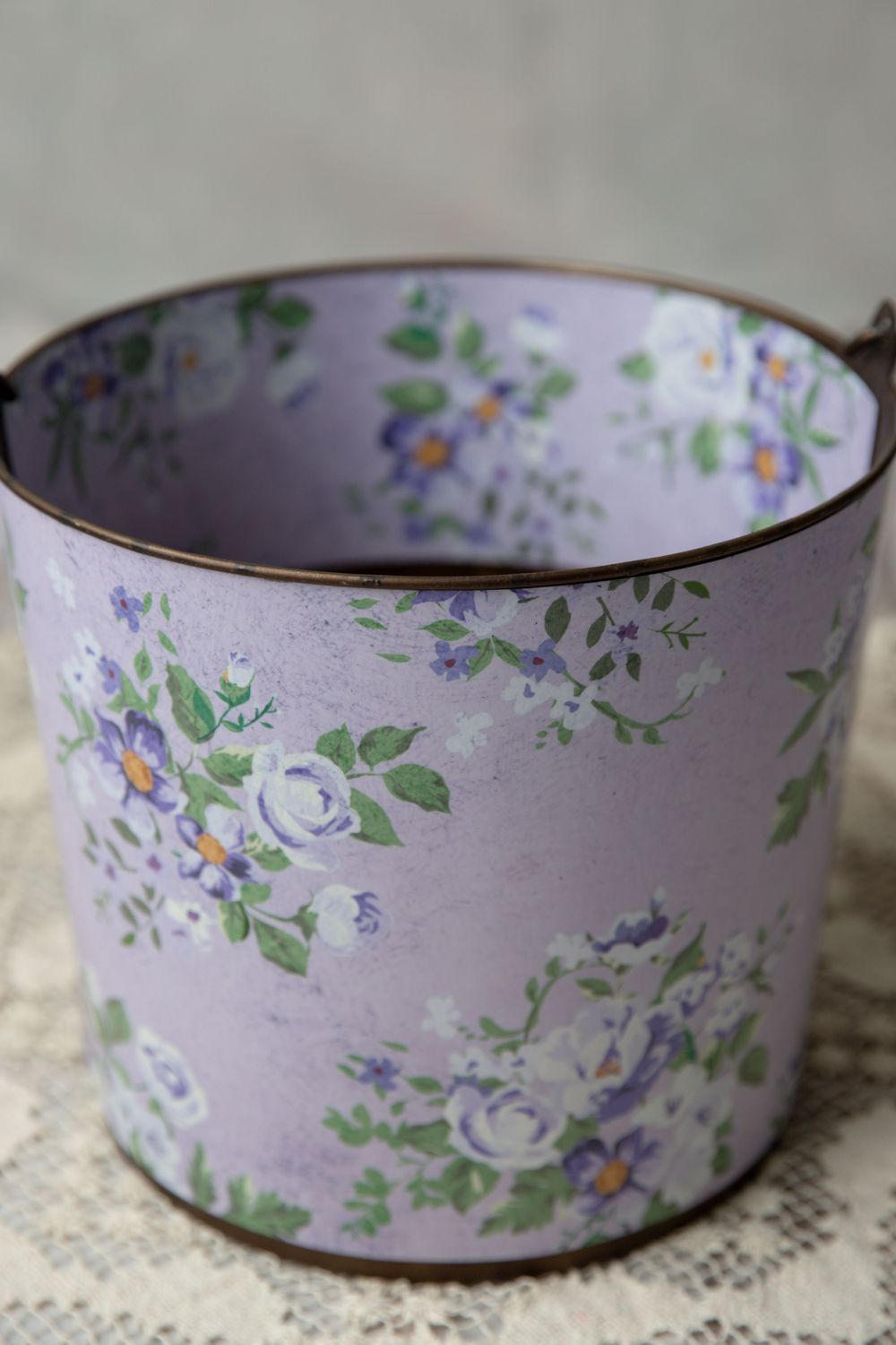 Vintage lavender floral tin bucket with purple roses and green leaves pattern, perfect for rustic home decor.