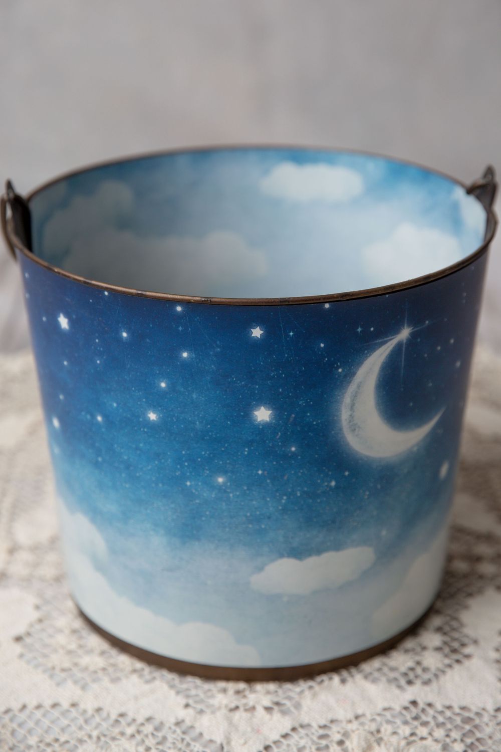 Decorative metal pail painted with a dreamy night sky scene featuring a crescent moon, stars, and clouds.