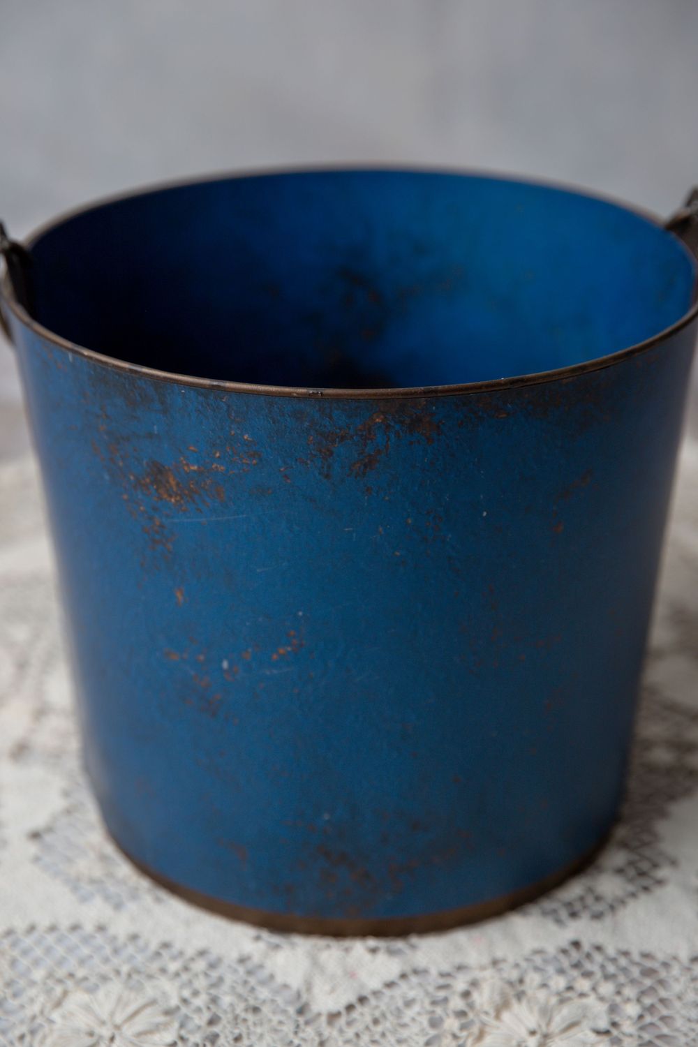 Vintage distressed blue metal bucket with rustic patina and worn enamel finish.