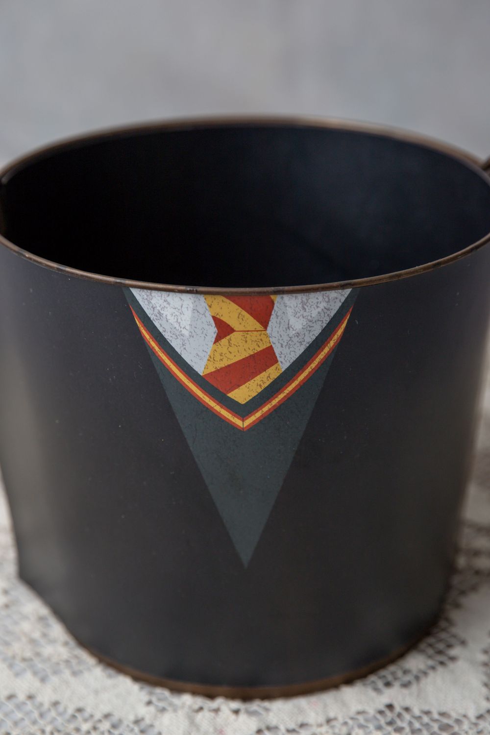 Black metal pot featuring a Harry Potter Gryffindor house uniform design with robe and striped tie.