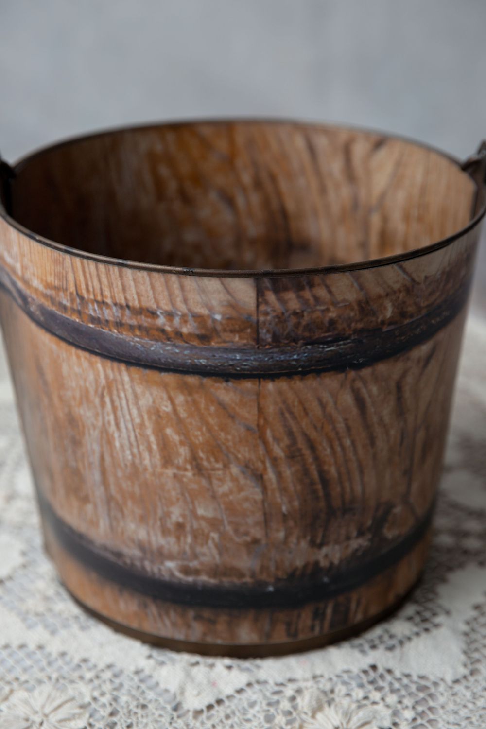 Rustic wooden barrel-style bucket with dark metal banding and natural oak wood grain texture.