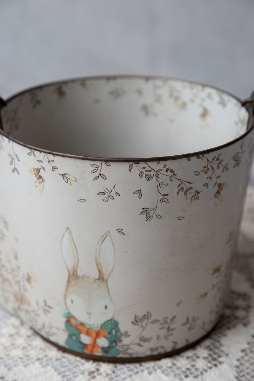 Vintage tin bucket with floral pattern and charming bunny illustration wearing a bow tie, perfect for Easter decor.