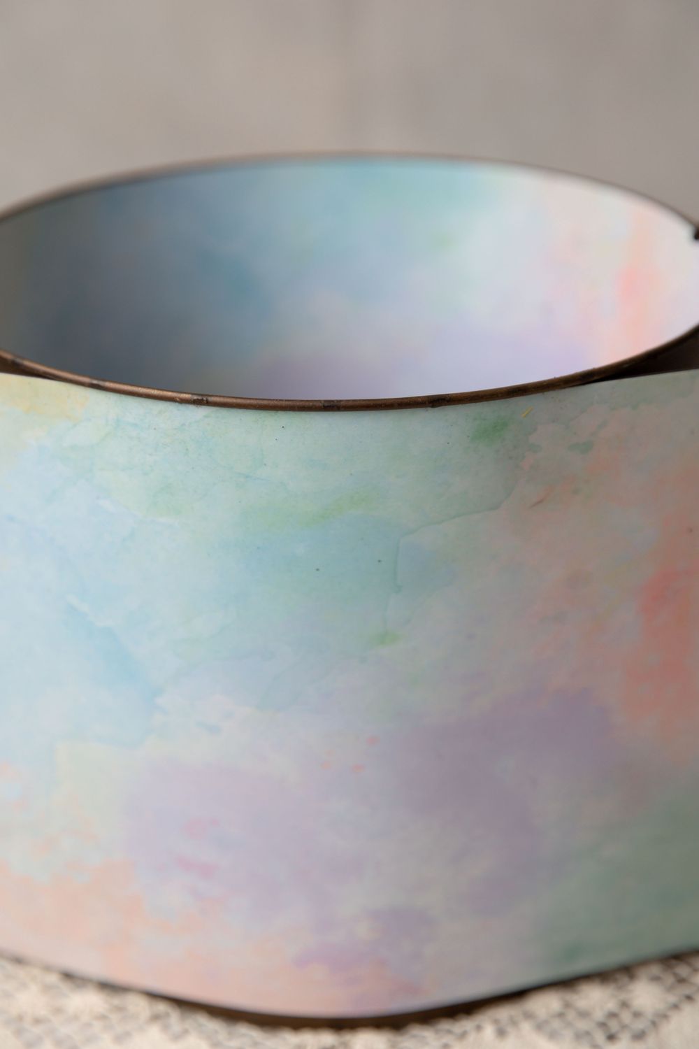 Pastel watercolor bangle bracelet with soft pink, blue, and green hues and dark trim.