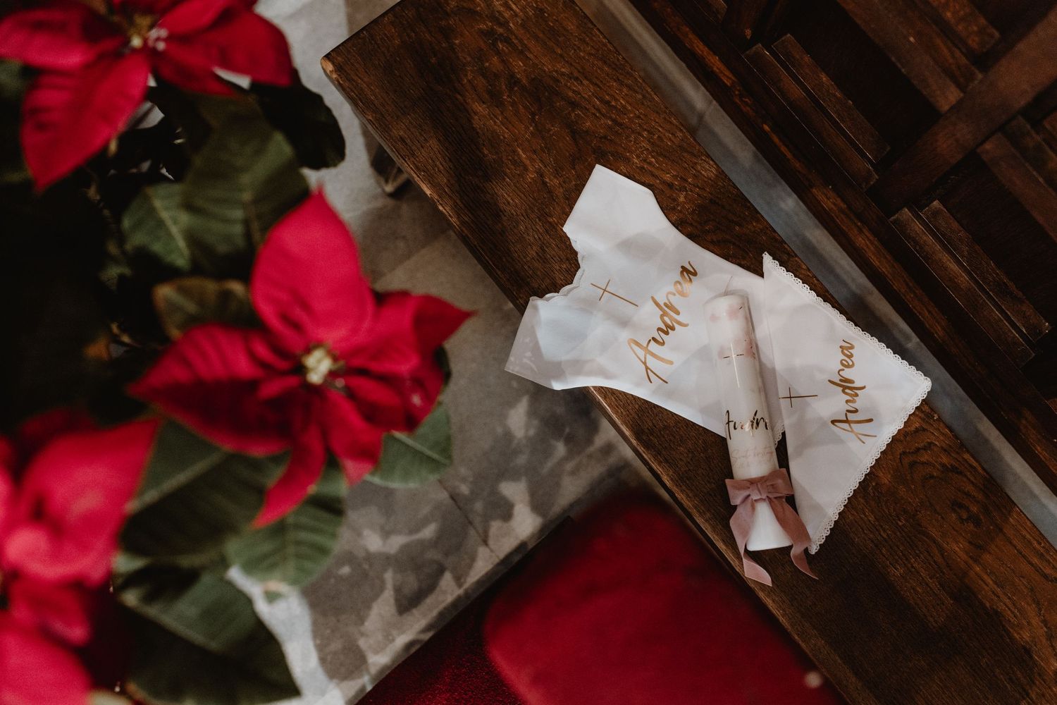 Red poinsettia flowers next to white cards on dark wooden surface.