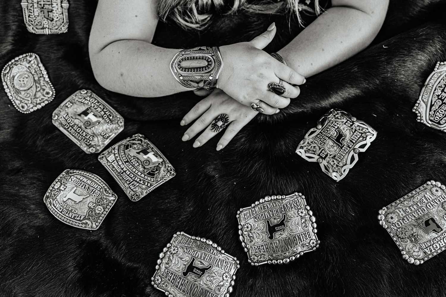 belt buckles displayed on fur with a woman's hands wearing jewelry for a western and livestock style senior session in South Georgia
