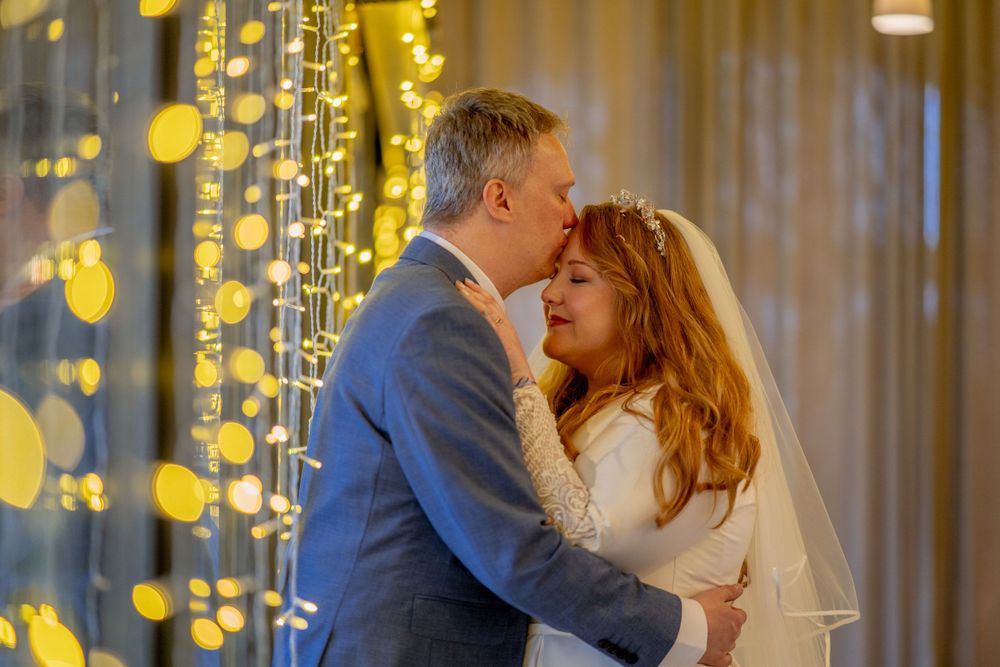 A romantic wedding moment captured with twinkle lights creating a magical bokeh effect in the background.