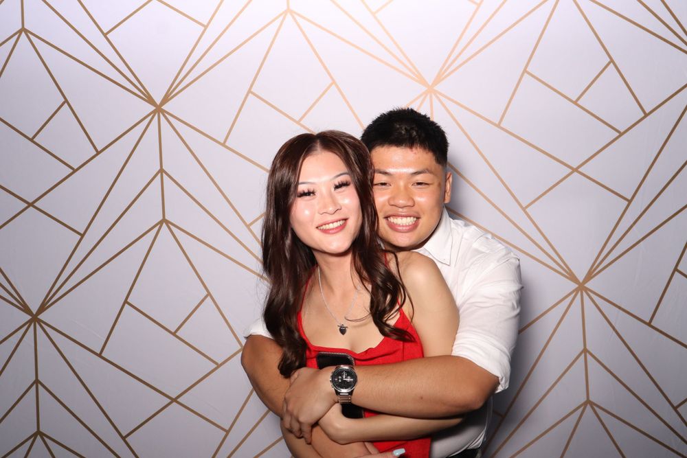Couple embracing and smiling against a geometric patterned backdrop.