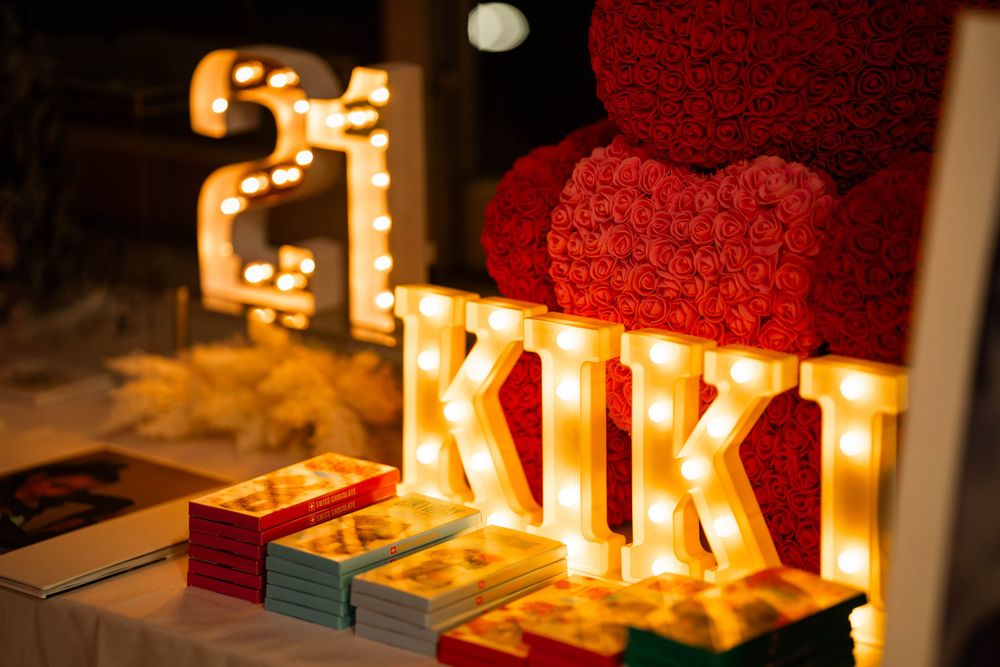 Illuminated event decor featuring light-up 'KIKI' sign with red rose decoration.