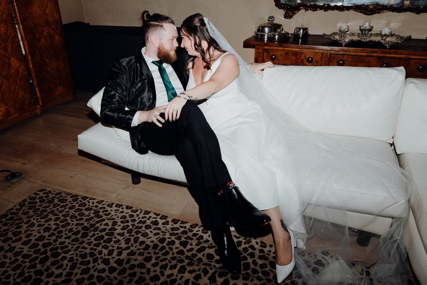 A newlywed shared an intimate moment while sitting on a white couch, captured by Apertured Media Auckland Wedding Photographer.