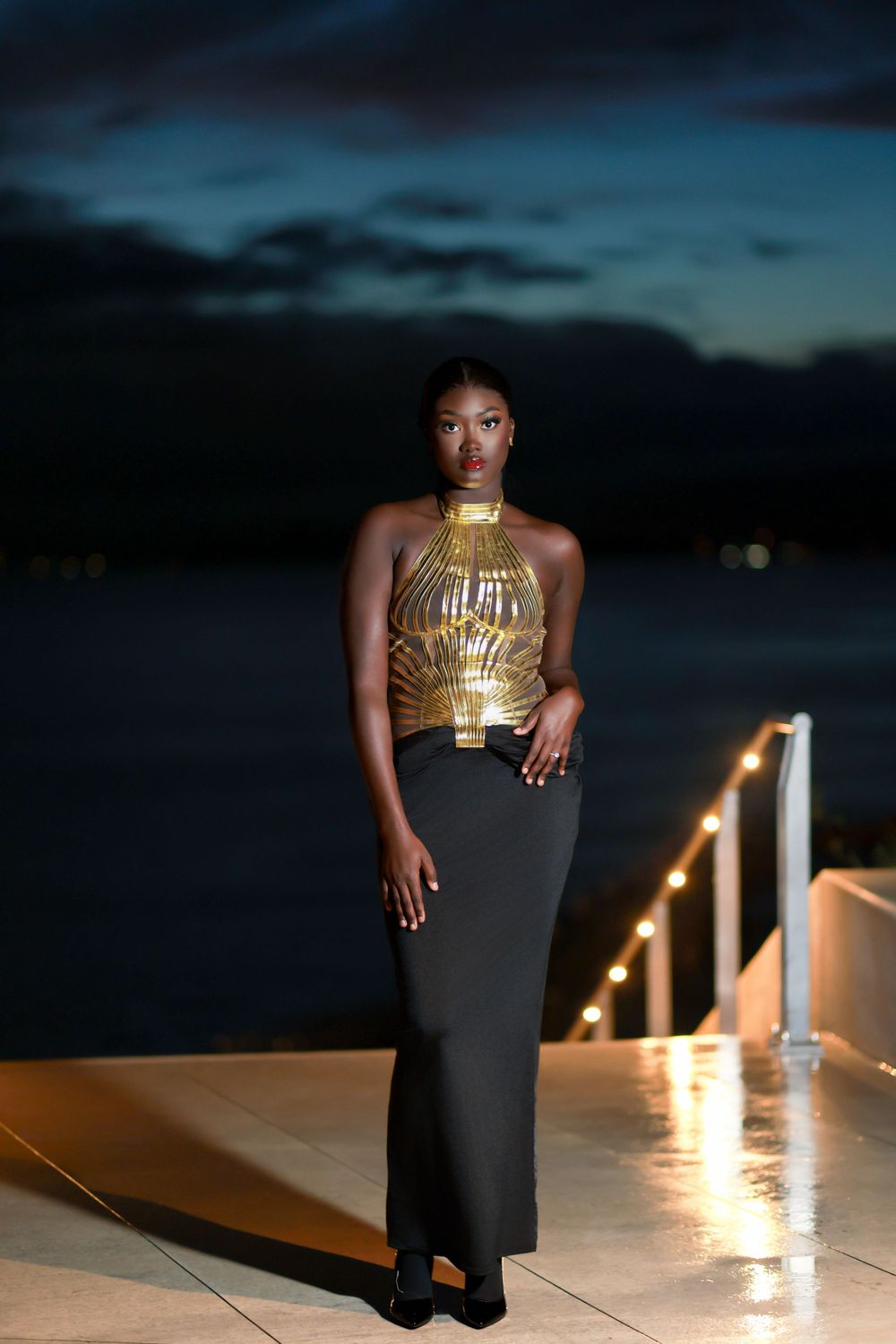 Dramatic nighttime fashion photo in gold top and black maxi skirt.