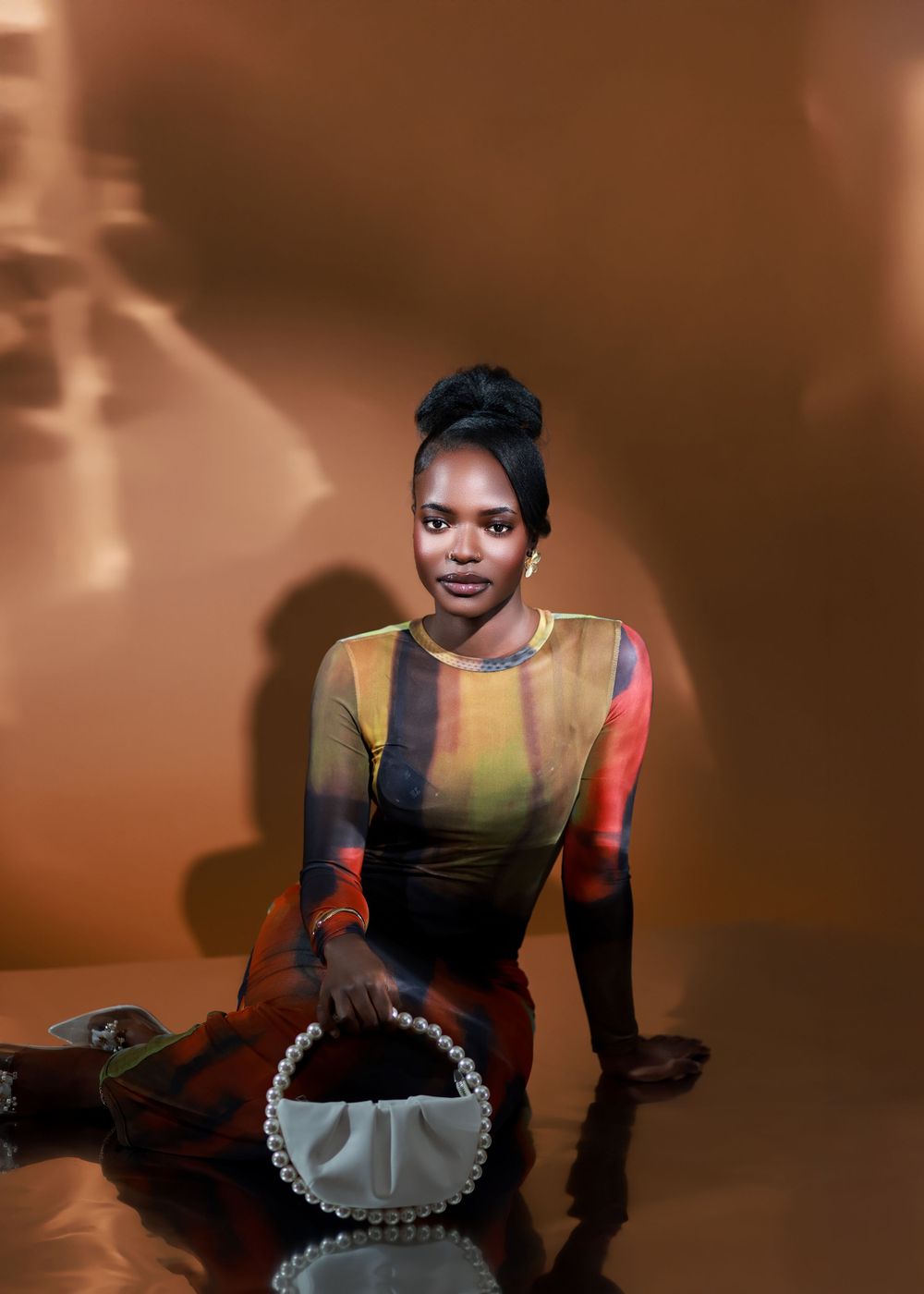 A studio fashion shot showcasing a multicolored fitted dress and structured white handbag.