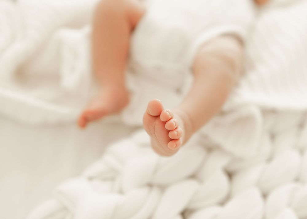 Close-up of tiny baby feet resting on soft white blanket or fabric.