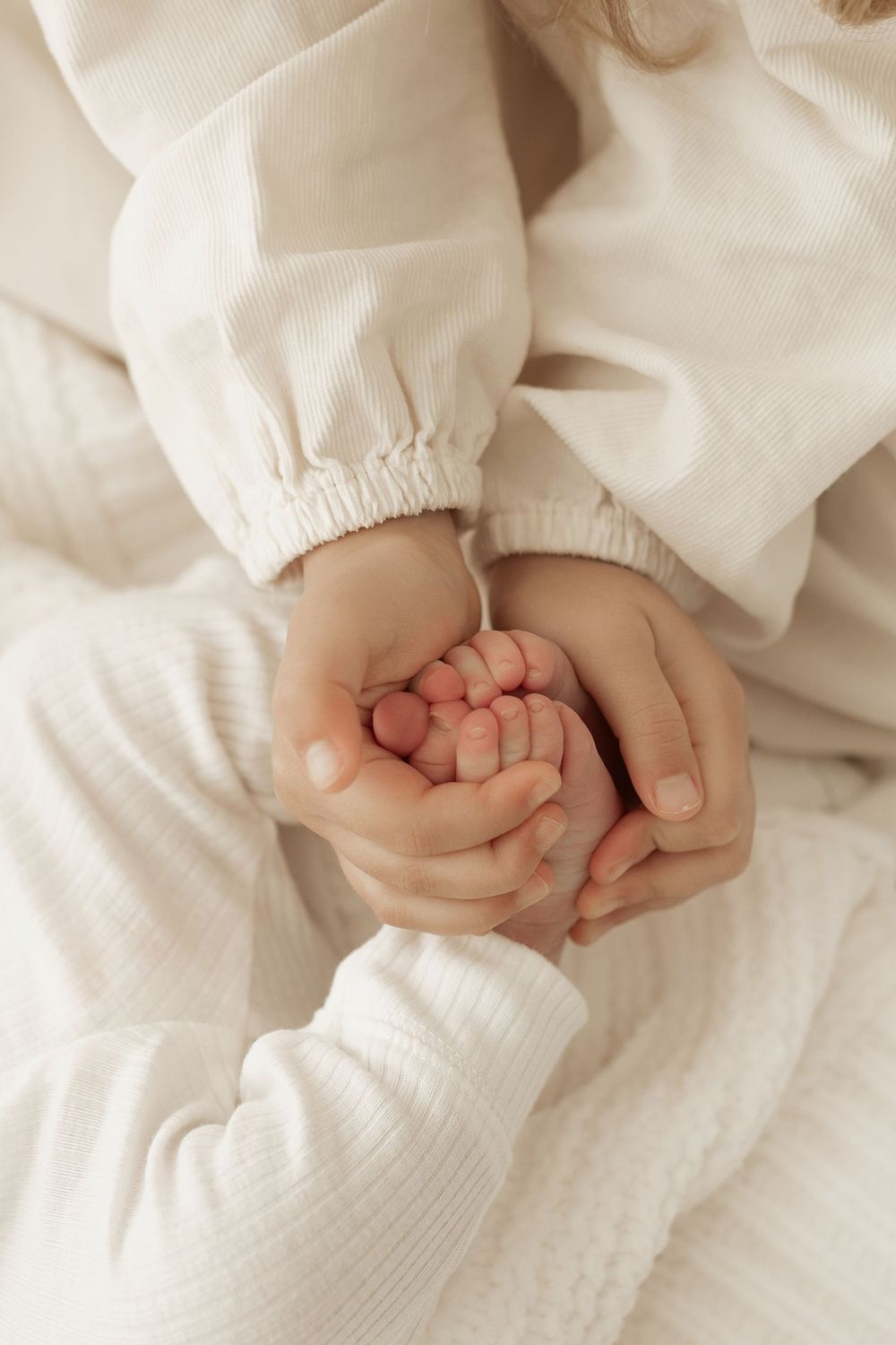 Tiny newborn baby toes and fingers wrapped in soft white fabric.