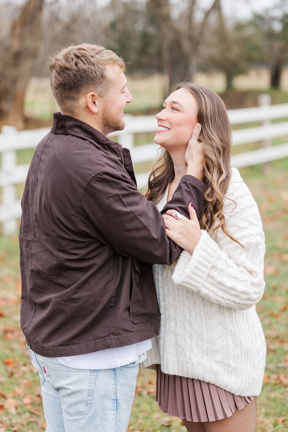 Couple sharing intimate moment outdoors wearing sweaters and casual attire.