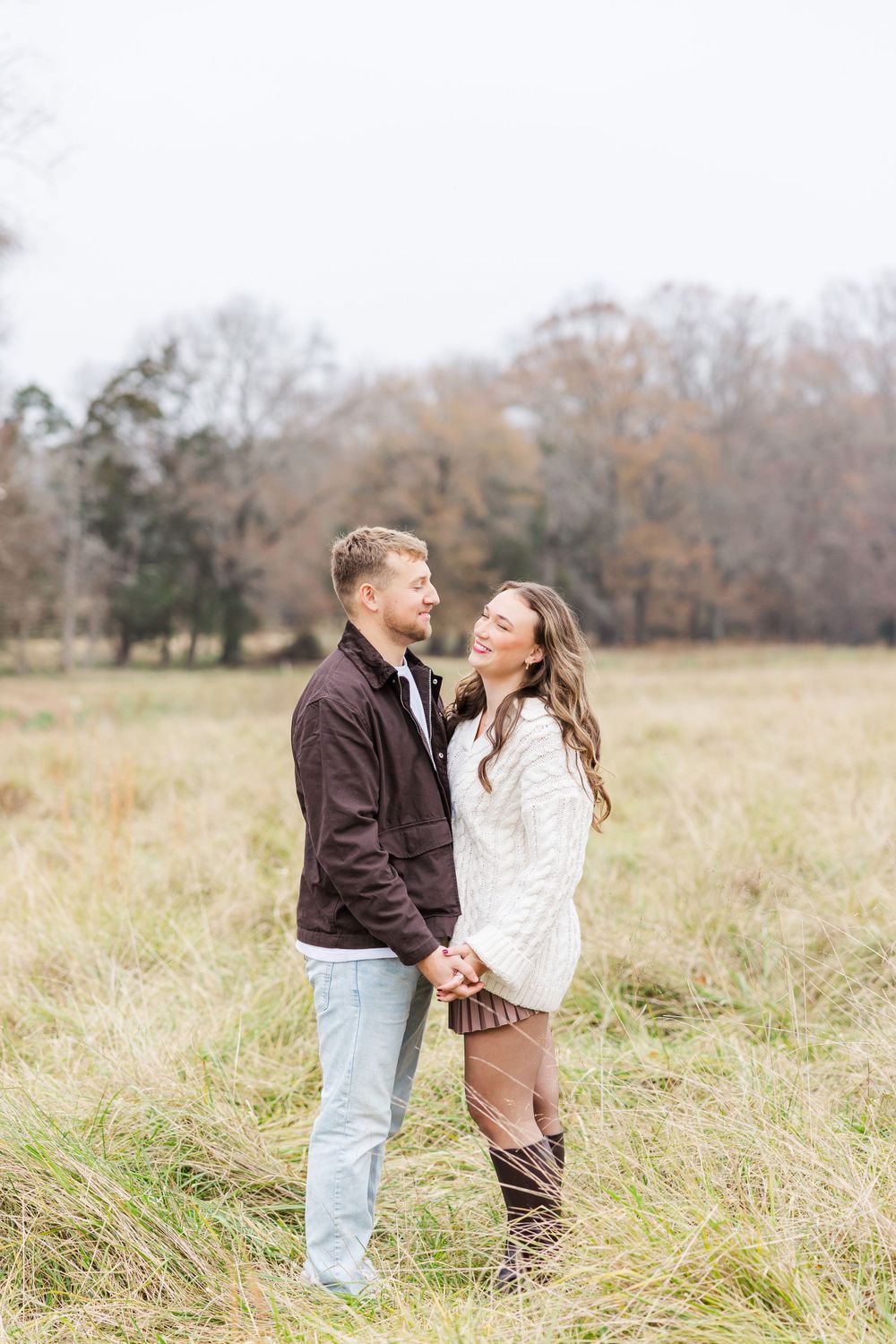 A couple shares an intimate moment in a autumn field wearing contrasting sweaters.