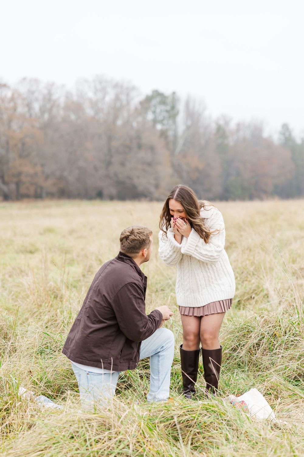 An emotional reaction to a marriage proposal in a scenic field setting.