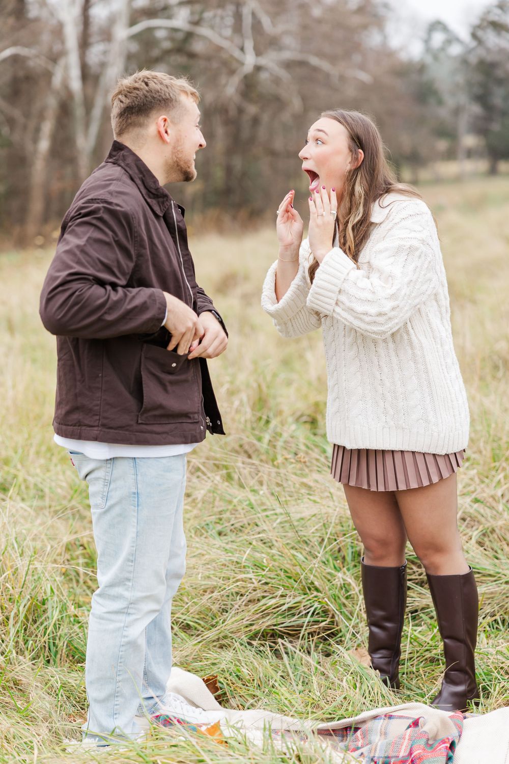 A joyful moment captured during a surprise proposal in an autumn field.