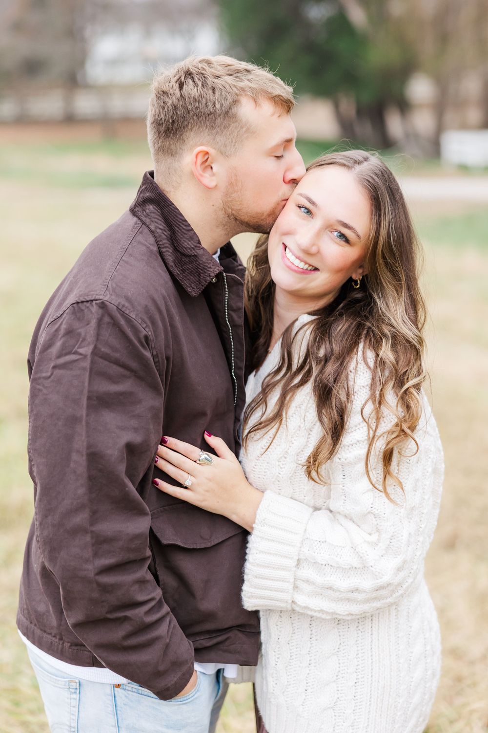 An intimate moment between a couple wearing casual fall attire in an outdoor setting.