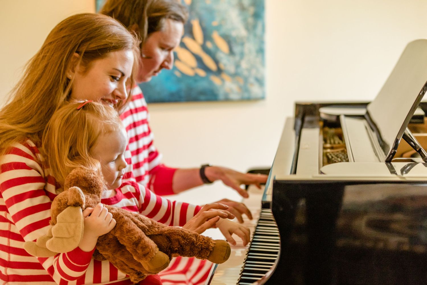 Family gathered around piano keys during a musical moment at home.