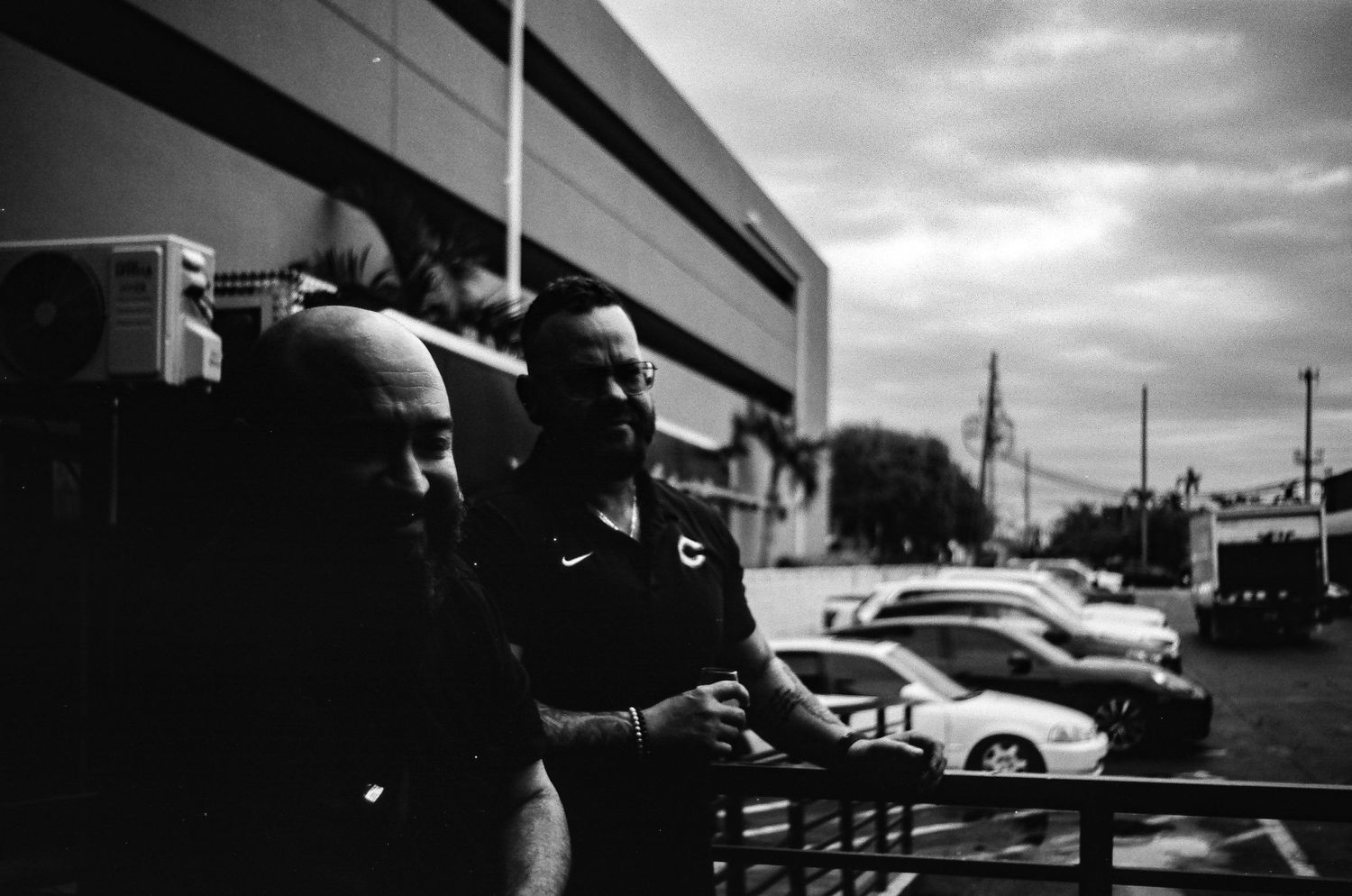 People standing outside a building in a moody black and white streetscape.