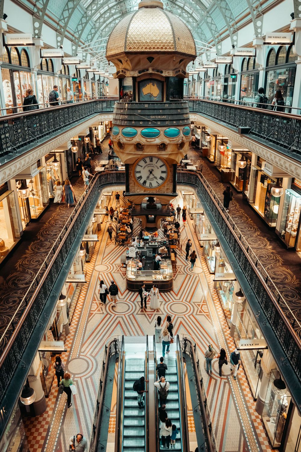 Interior view of Queen Victoria Building shopping arcade showing ornate Victorian architecture and busy retail spaces.