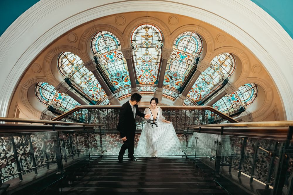 Grand architectural staircase with ornate stained glass windows in an art deco style.