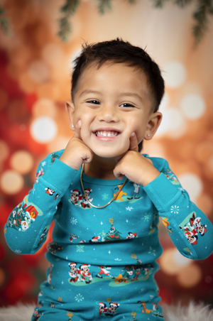 Holiday portrait with turquoise snowflake patterned shirt against warm bokeh lights.